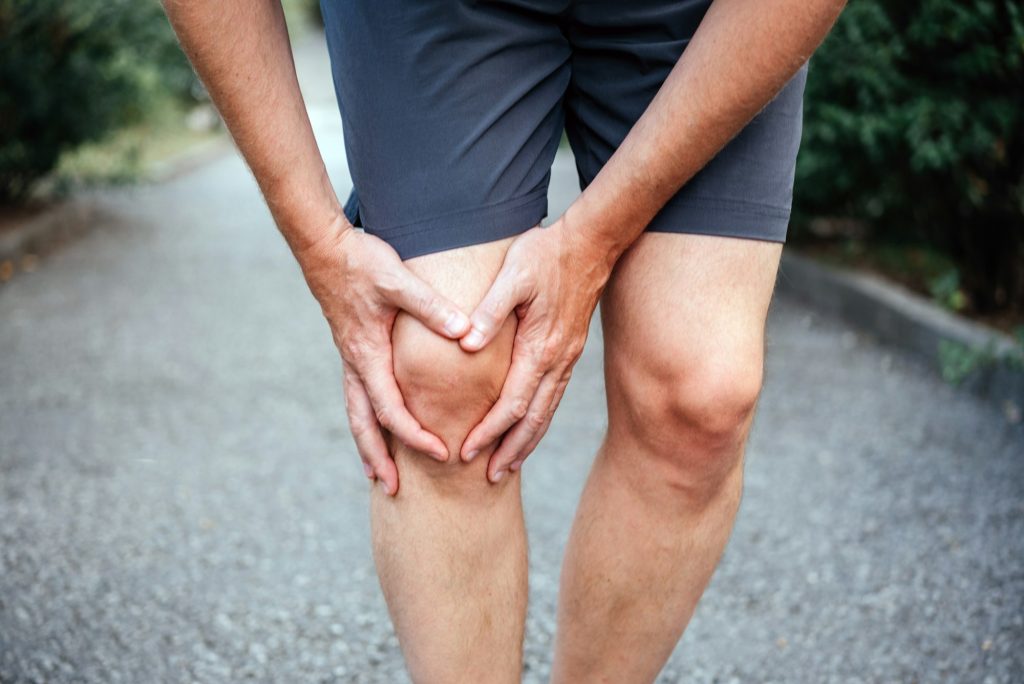 A male athlete having difficulty in straightening or bending the knee because of bursitis